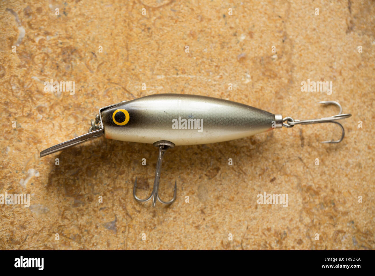 A vintage fishing lure equipped with treble hooks photographed on a stone  background. These type of lures are often called plugs and are designed to  c Stock Photo - Alamy