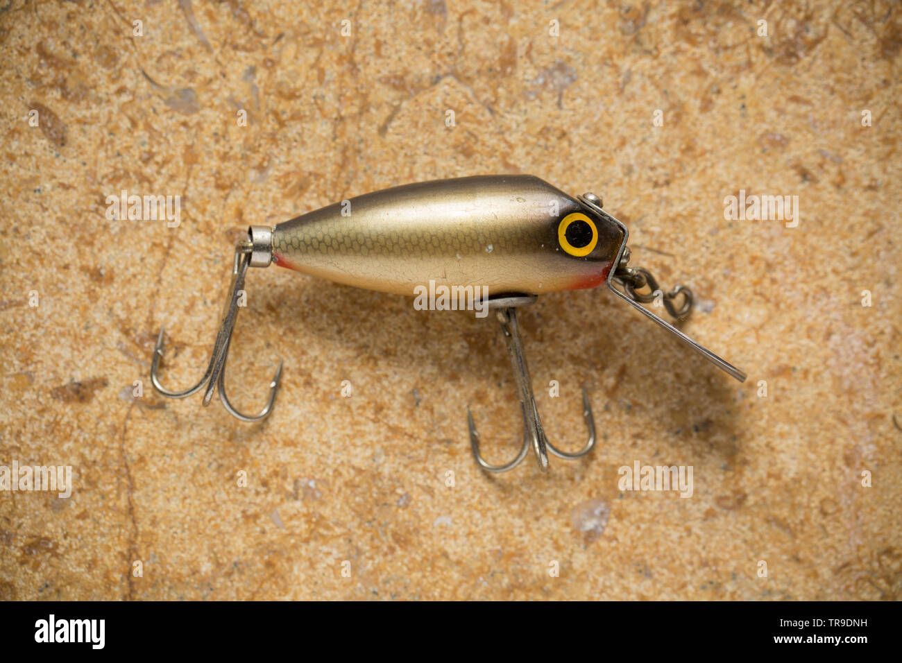 A vintage fishing lure equipped with treble hooks photographed on