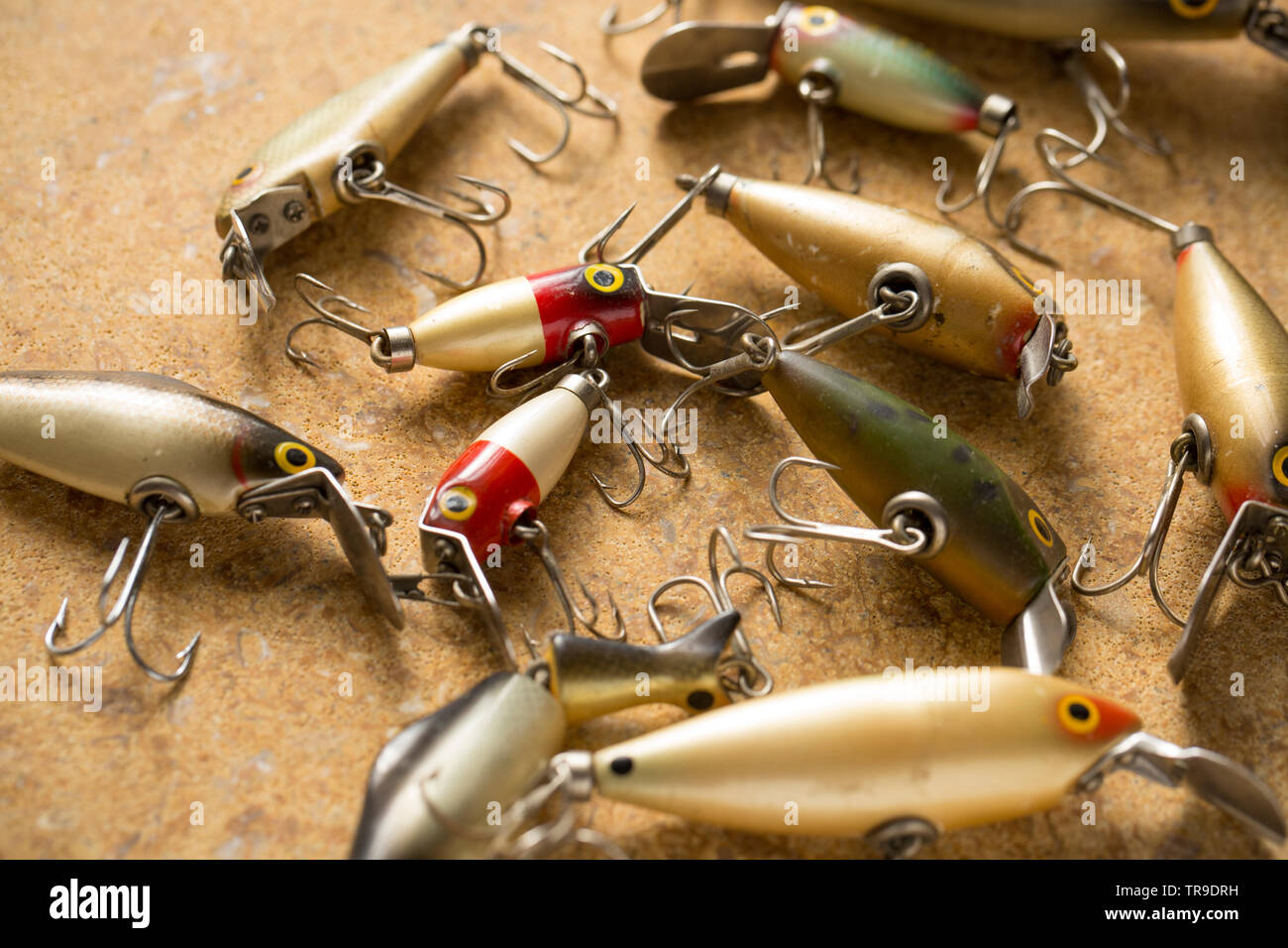 Vintage fishing lures equipped with treble hooks photographed on a stone background. These type of lures are often called plugs and are designed to ca Stock Photo