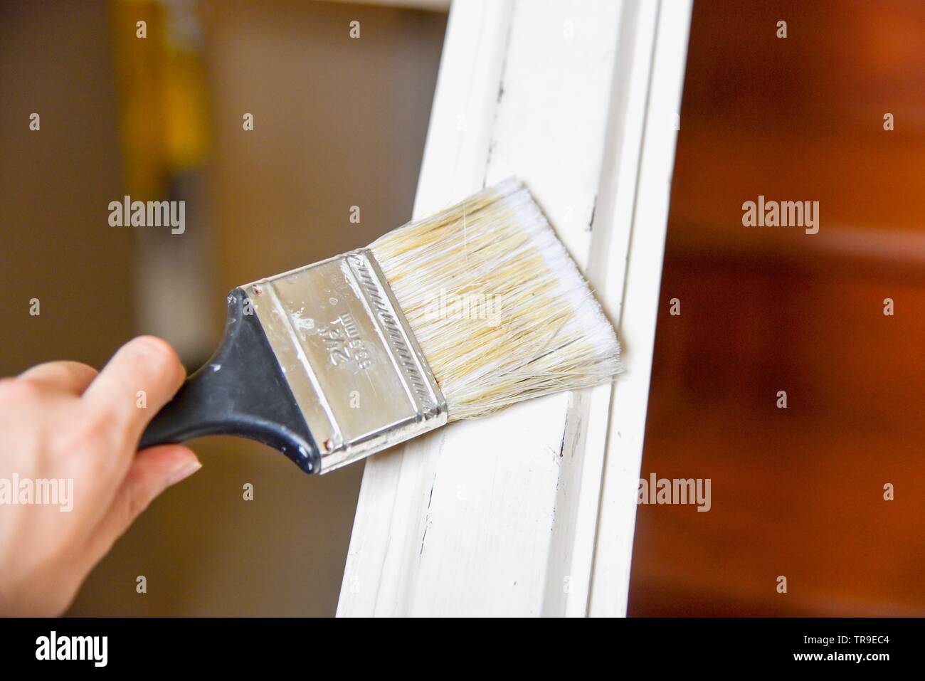 Hand Holding Paint Brush and Painting Stair Handrails with White Color