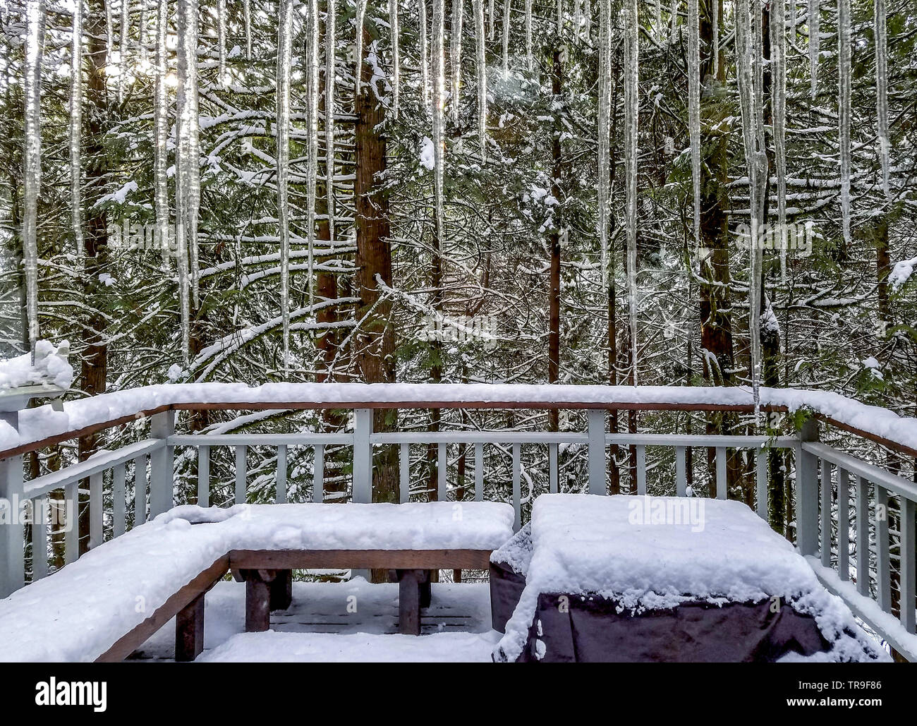 Icicles drip from overhang above glass sliding door during rare Seattle snowfall. Stock Photo