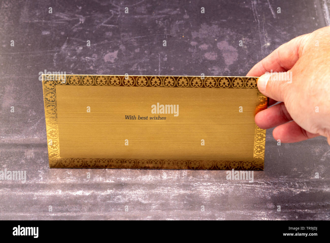 A golden Indian gift envelope with a hand and a slate background Stock