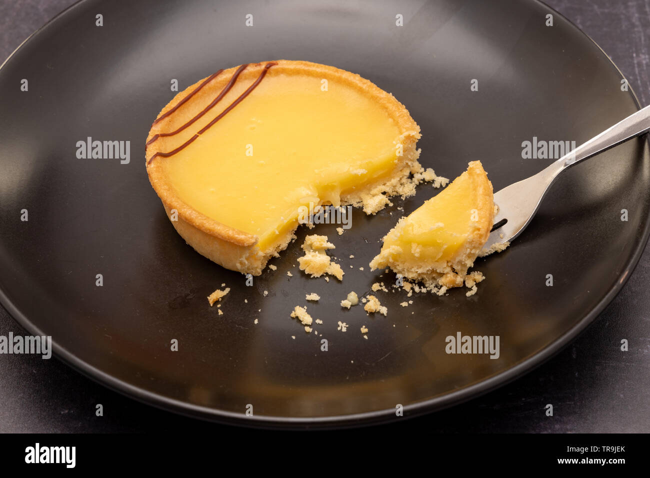 Two lemon tarts on a slate background, with dessert fork Stock Photo