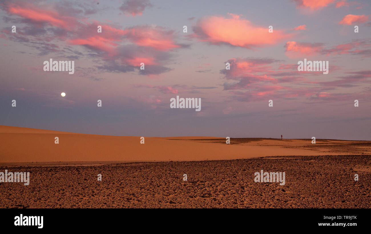 A beautiful African sunset in the western desert of Sudan with colourful clouds and sky and the flat desert landscape Stock Photo