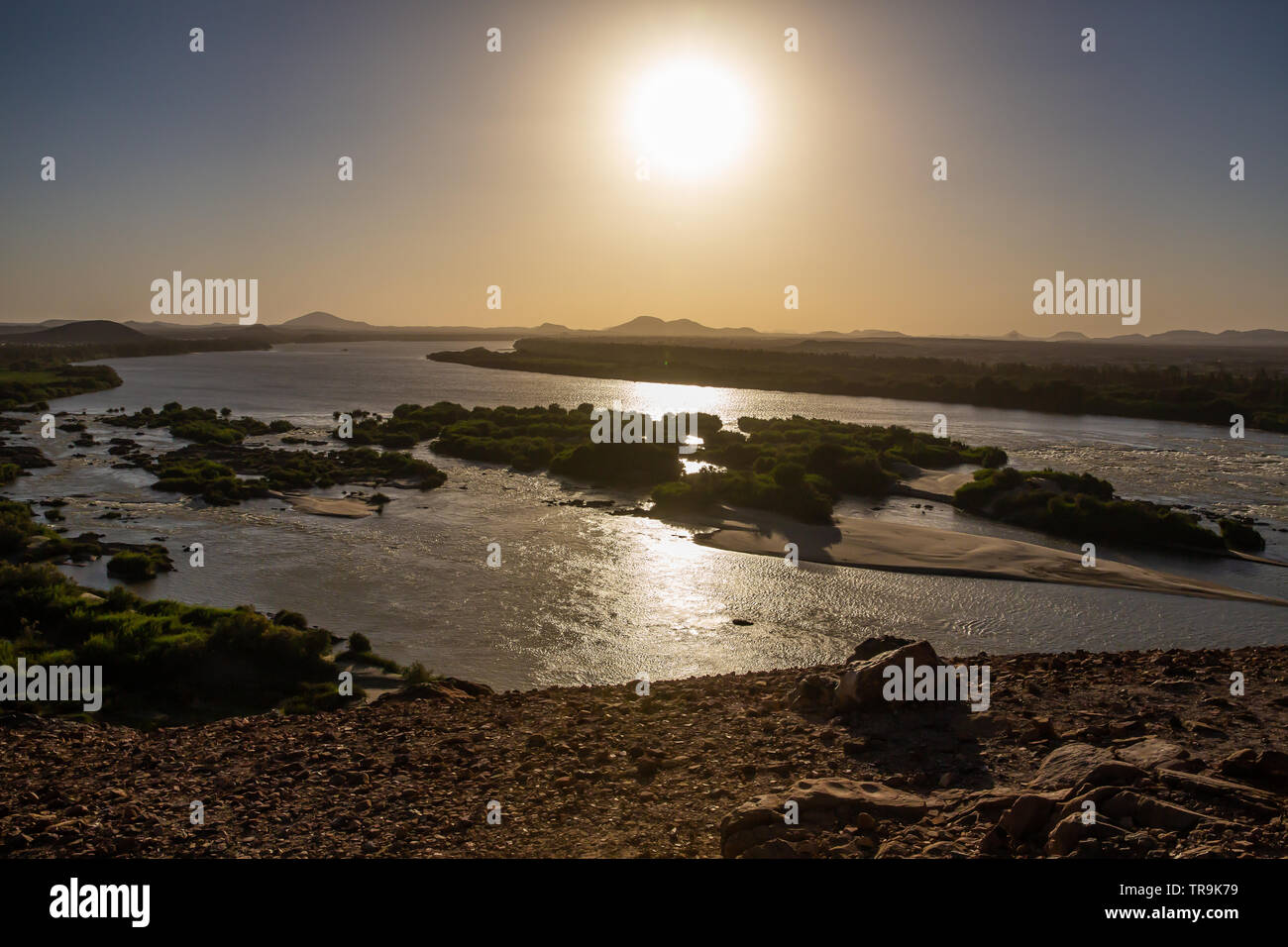 The early evening sun is reflected brightly in the waters of the third cataract of the river Nile in the Nubian region of Sudan Stock Photo