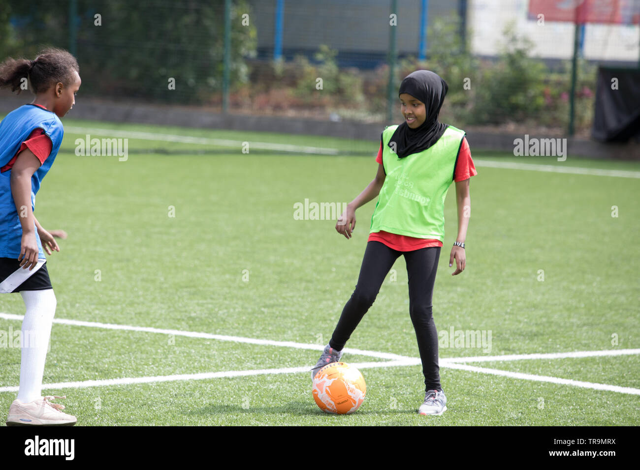 Muslim girls playing football on an astroturf training pitch. Some are wearing hijabs (headscarves). Stock Photo