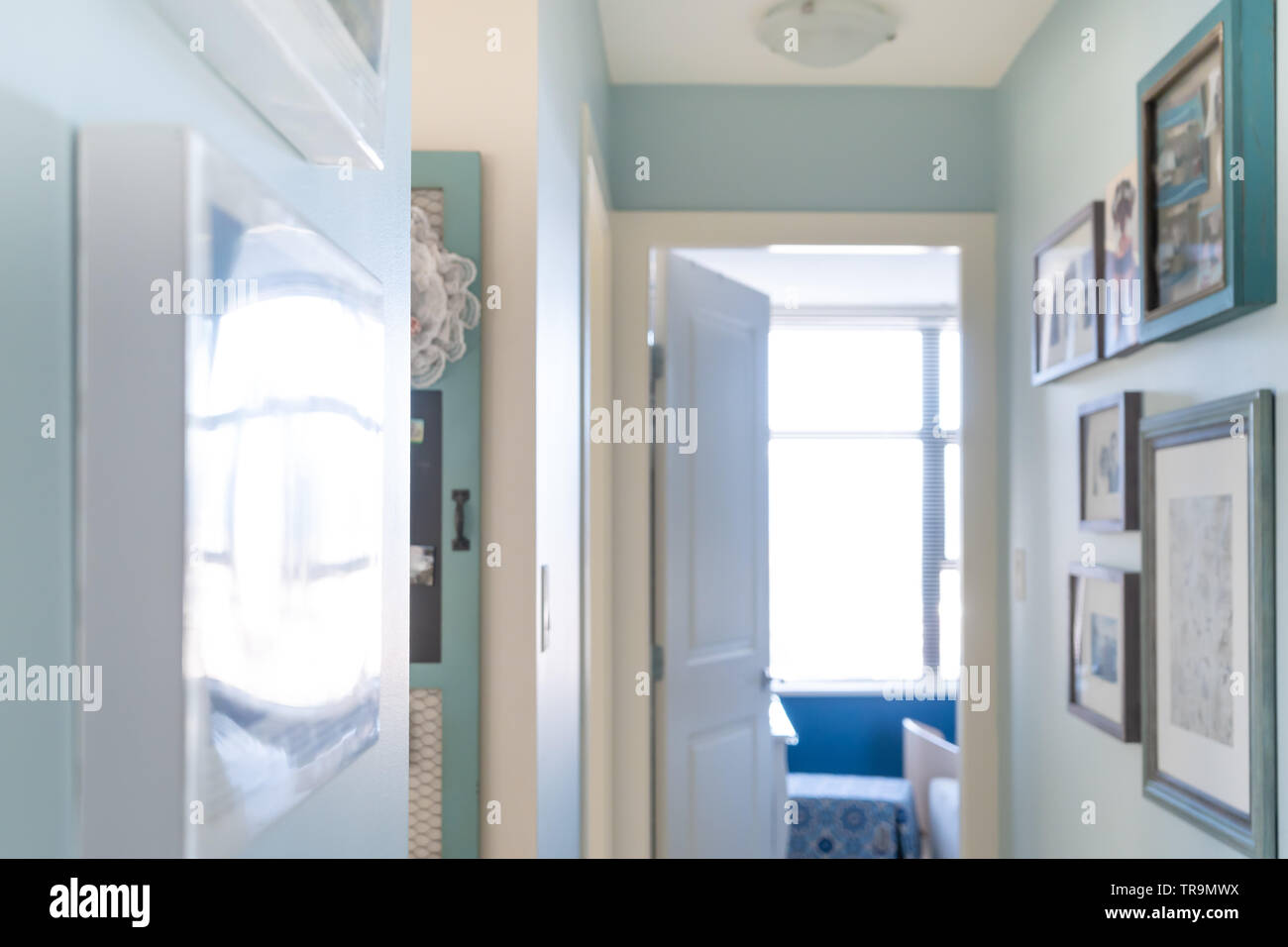 Home apartment hallway with picture frames as wall art, for interior decor with matching blue design and painter's work. Scene is a little hazy. Stock Photo