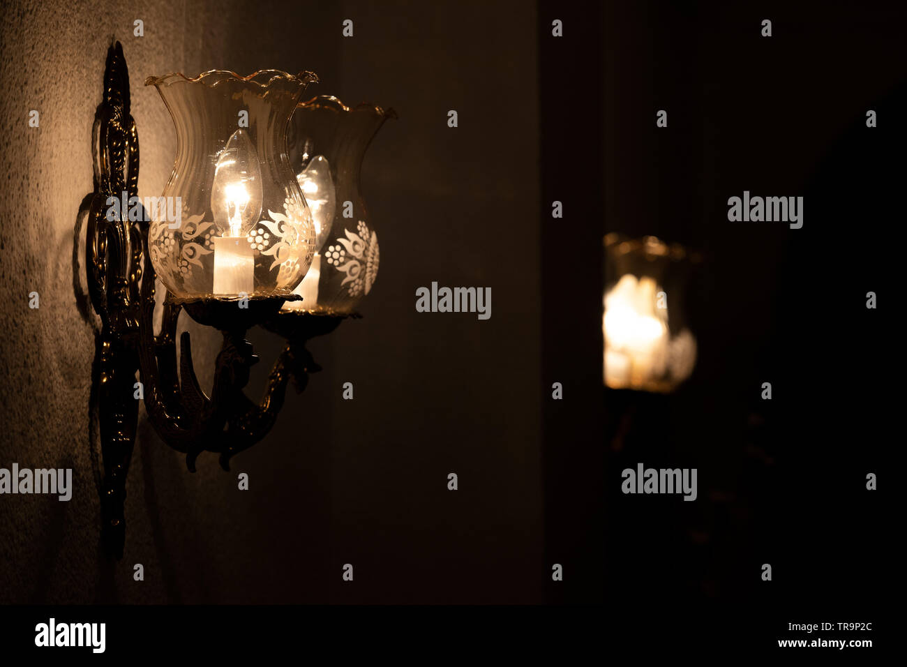 Wall lamps in gloom producing a disturbing atmosphere Stock Photo
