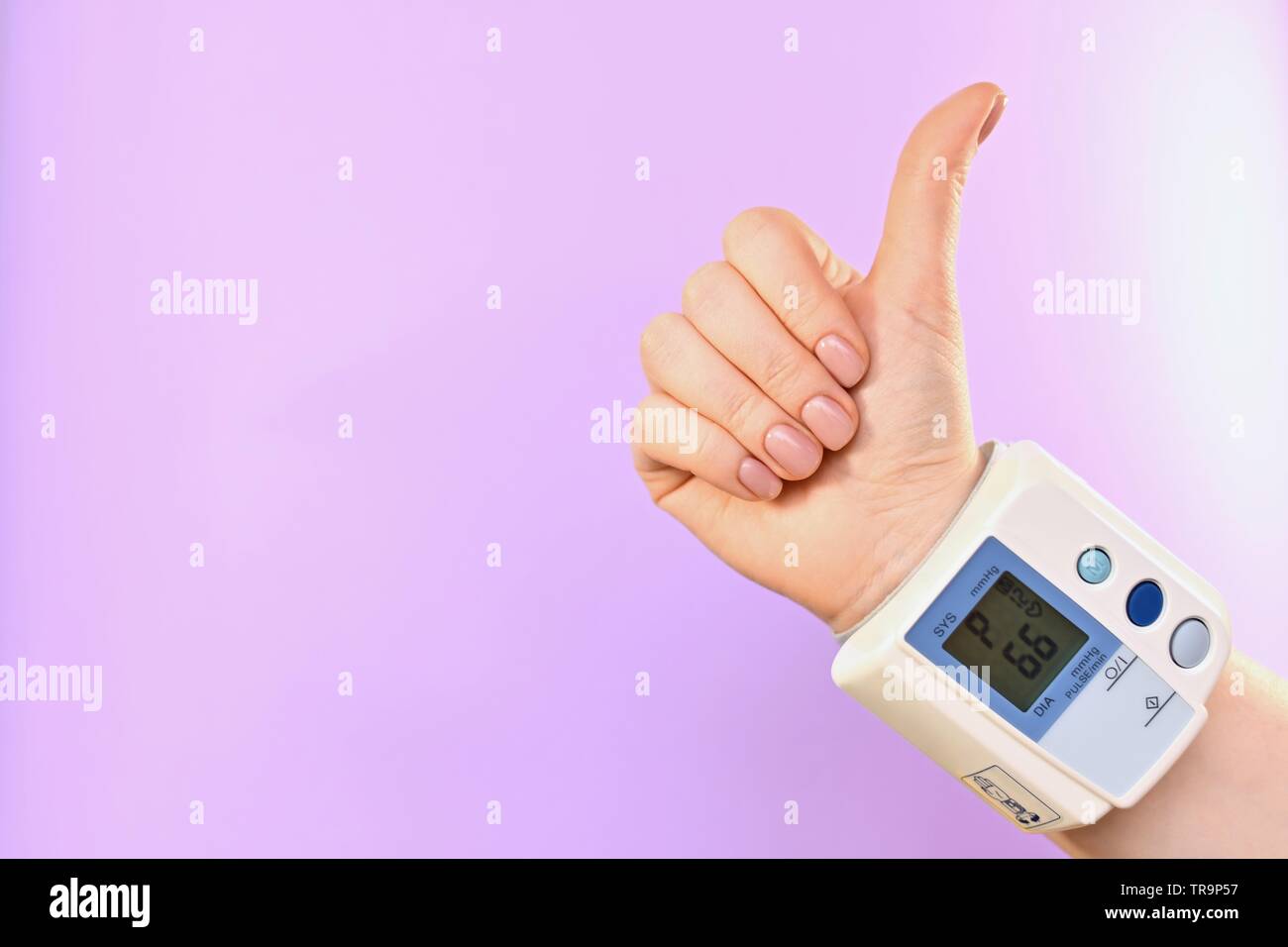 Hand and tonometer, buttoned at the wrist. Diagonally in the center, from the lower right corner. On a purple background. On the scoreboard heart rate Stock Photo