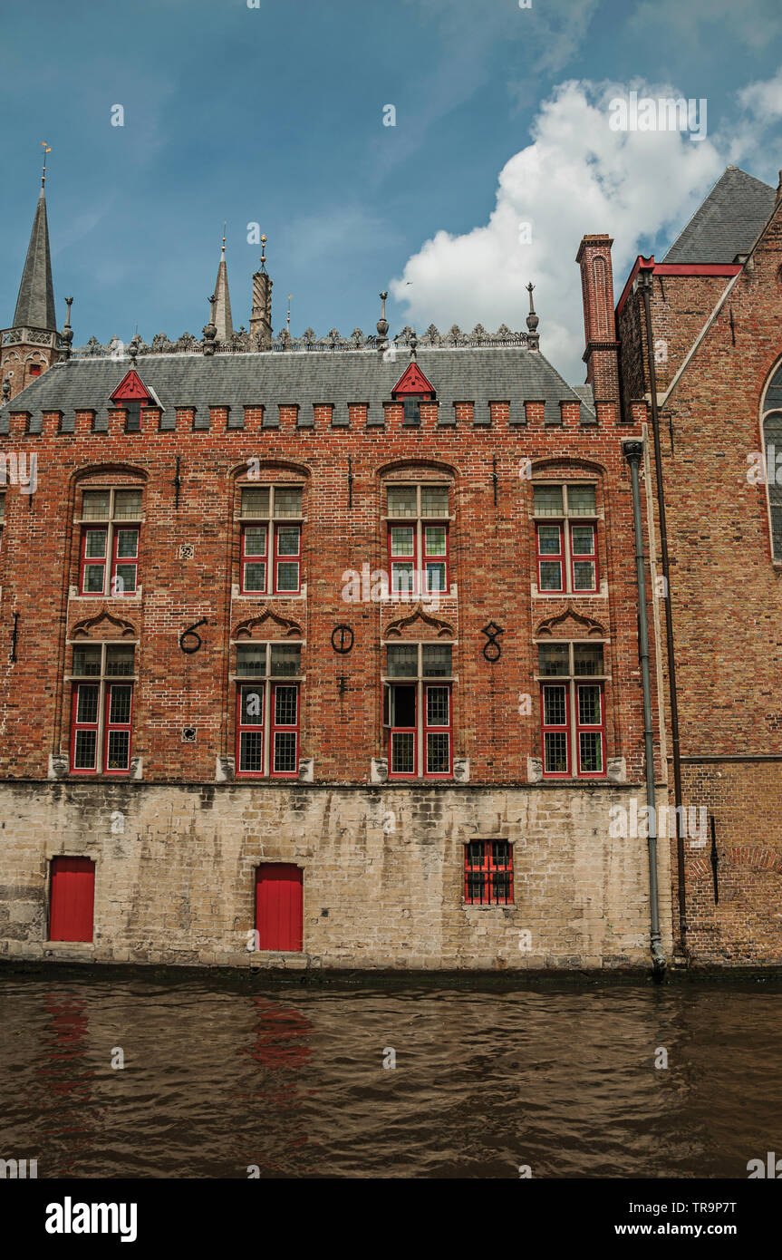 Old brick buildings on the canal edge in a sunny day at Bruges. Charming town with canals and old buildings in Belgium. Stock Photo