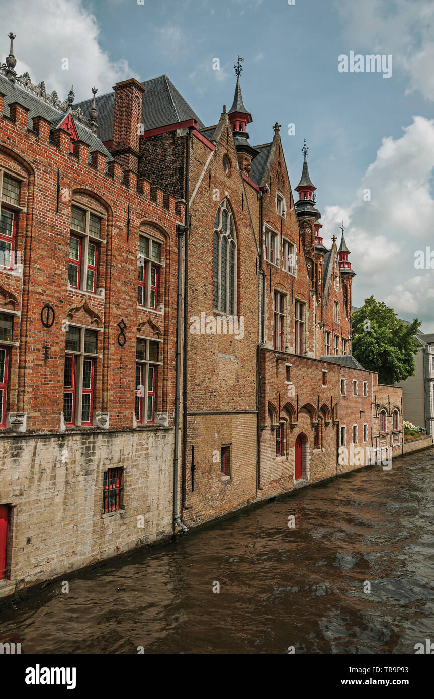 Old brick buildings on the canal edge in a sunny day at Bruges. Charming town with canals and old buildings in Belgium. Stock Photo