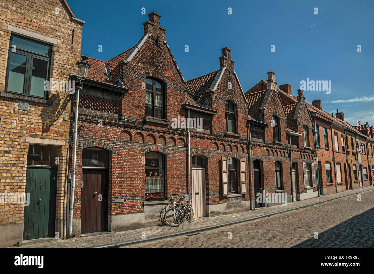 Brick facade of houses in typical Flanders style and bicycle, in street of Bruges. Charming town with canals and old buildings in Belgium. Stock Photo