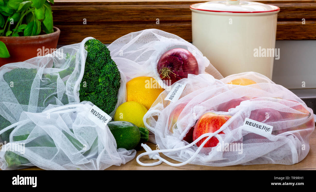 Fruit and Vegetables in reusable mesh bags, with reuse me labels, on kitchen counter, authentic real plastic free eco friendly shopping, working towar Stock Photo