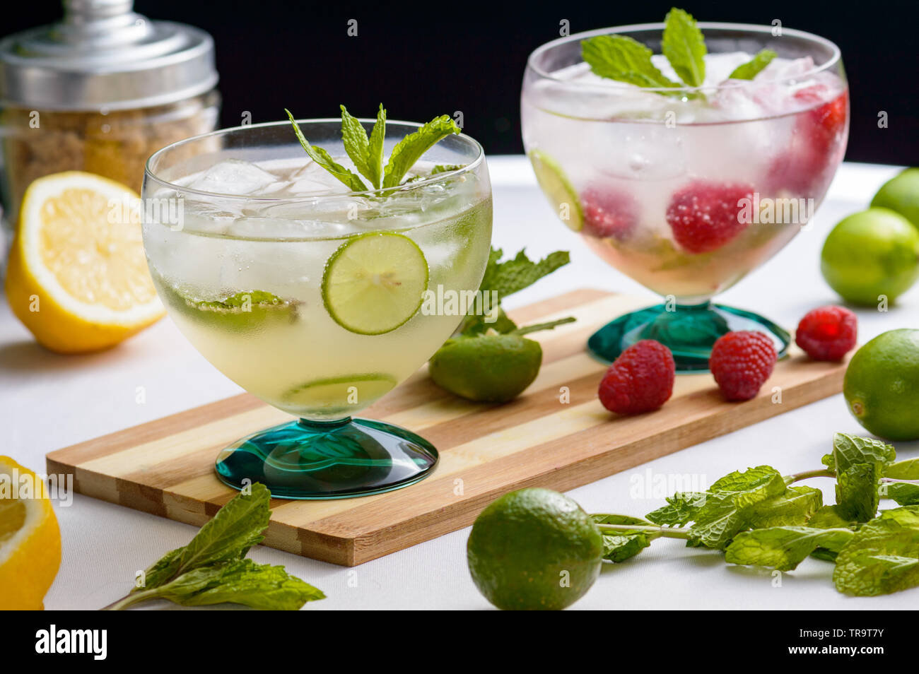 Mojito and raspberry mojito rum cocktail drinks with ingredients, limes, lemons, mint, brown sugar and raspberries. Concept for restaurants, food and Stock Photo