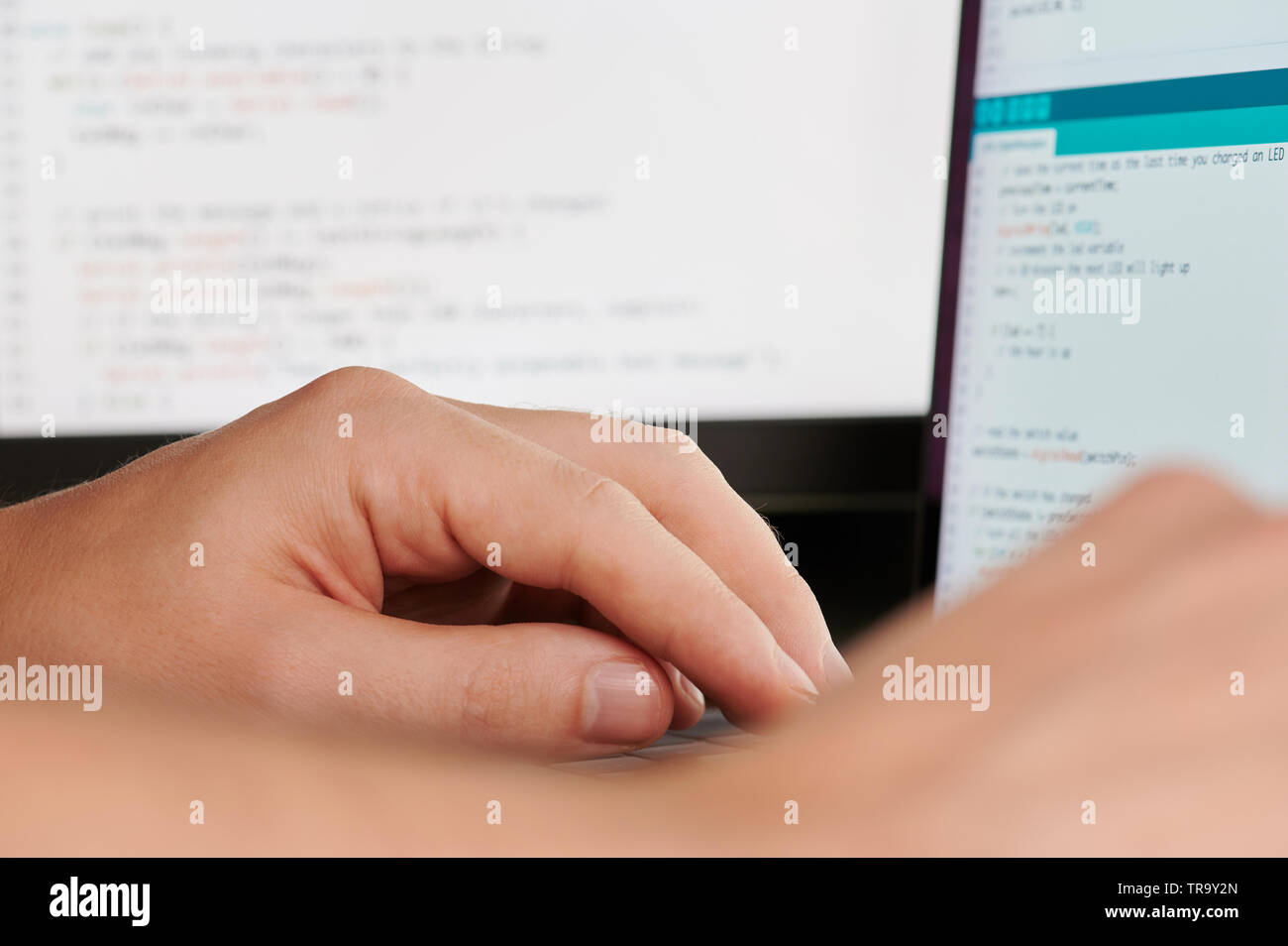 Programmer hands on blurred code background close up view Stock Photo