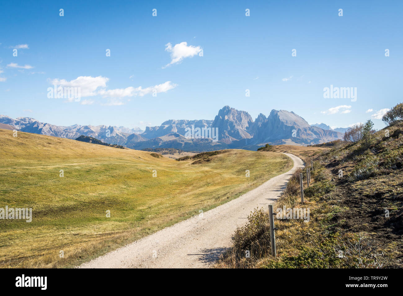 A long and winding gravel road high atop the Dolomites in northern Italy on a clear sunny day with blue skies and excellent visibility. Stock Photo