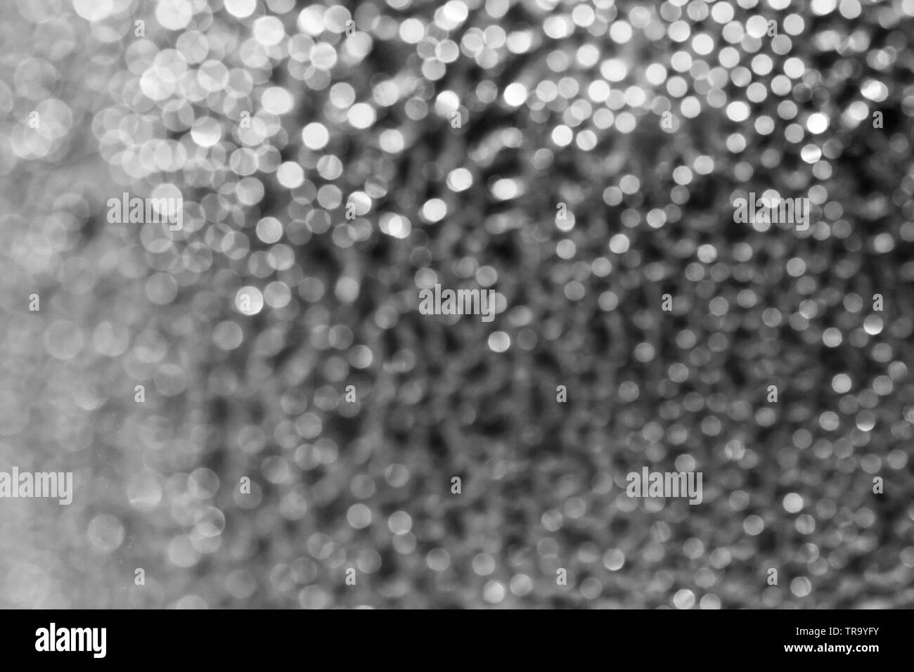 Blurred background of drops on the bottle wall. Blurred lights garland. Texture Stock Photo