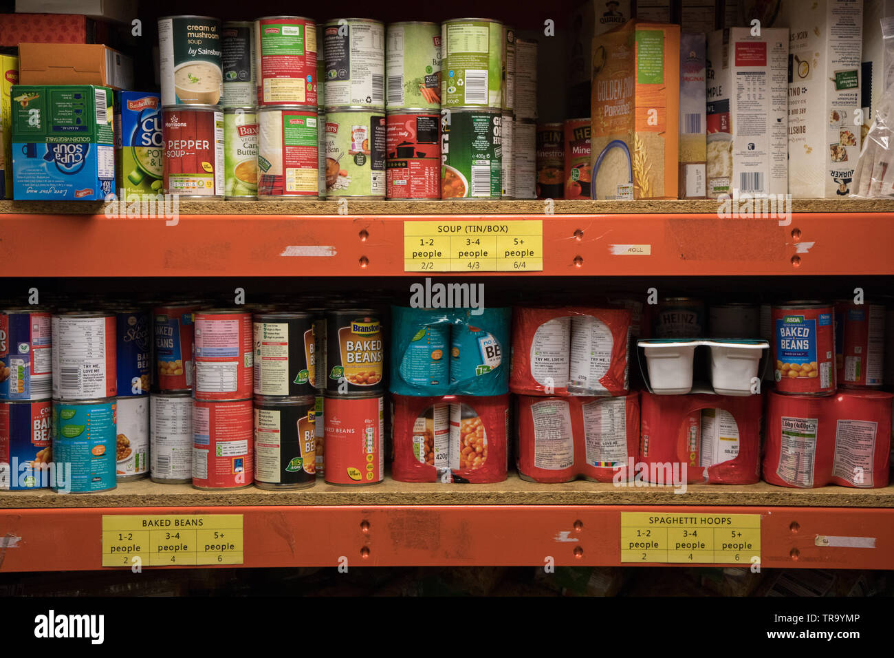 Tins of food stored on shelves at a food bank in Wembley, Greater London Stock Photo