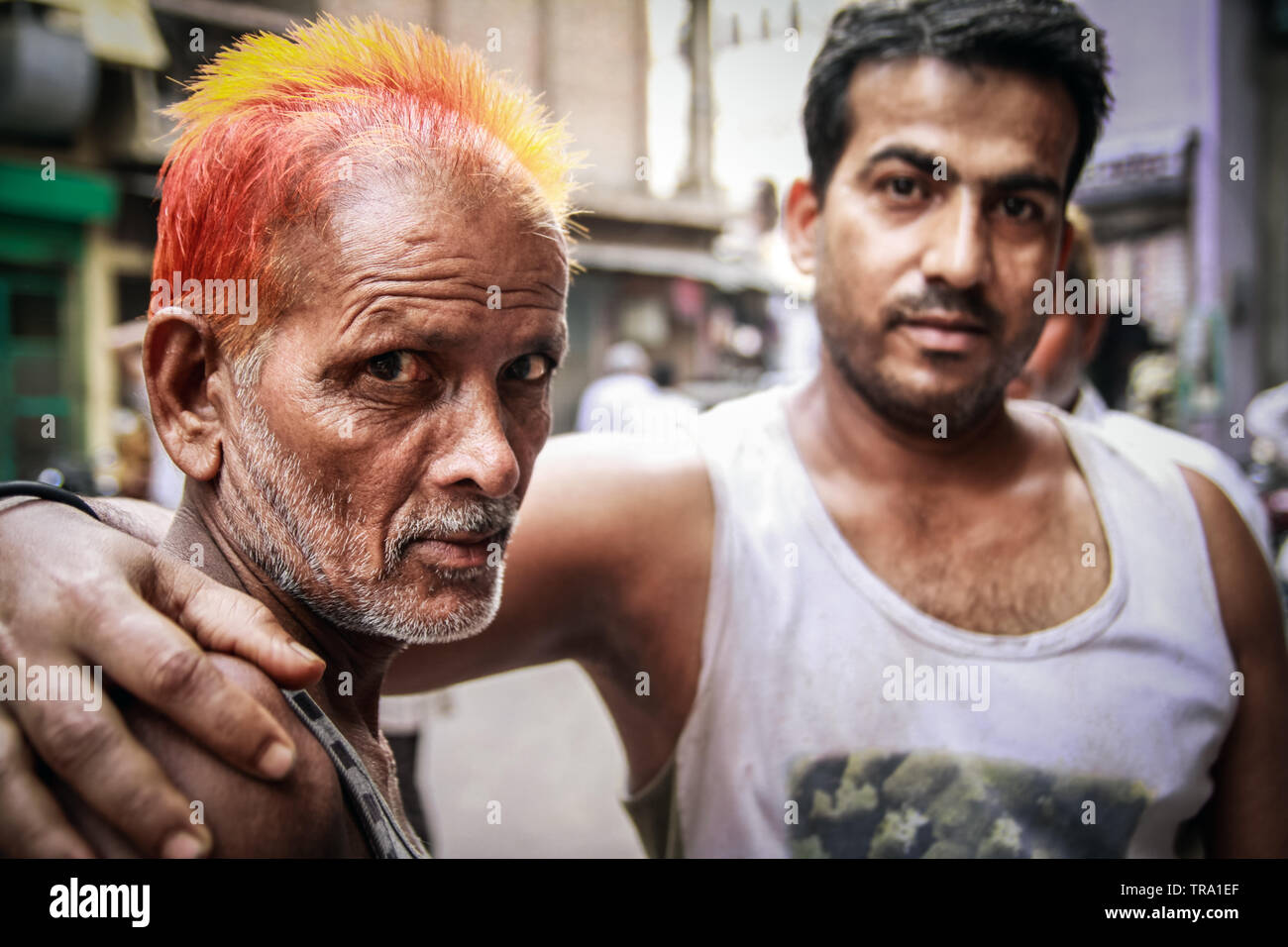 Two men on the streets of India with attitude, one with vivid henna dyed hair another a street wise and tough looking friend. A Reality portrait Stock Photo
