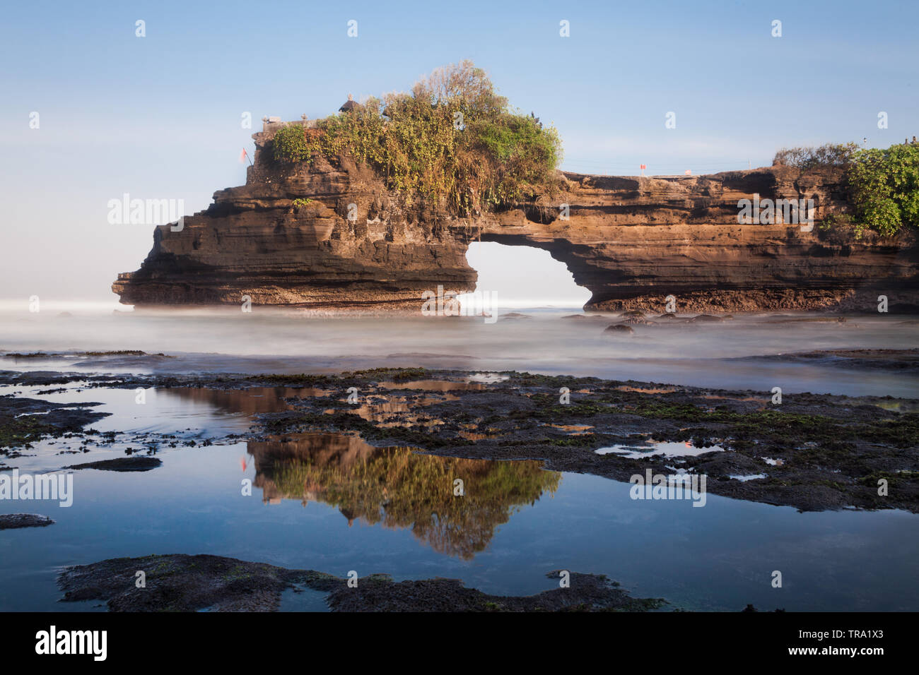 Stunning naturally weathered rock arch of Batu Bolong part of the World famous Tanah Lot rock Temple in Bali, Indonesia. Wide angle seascape image Stock Photo