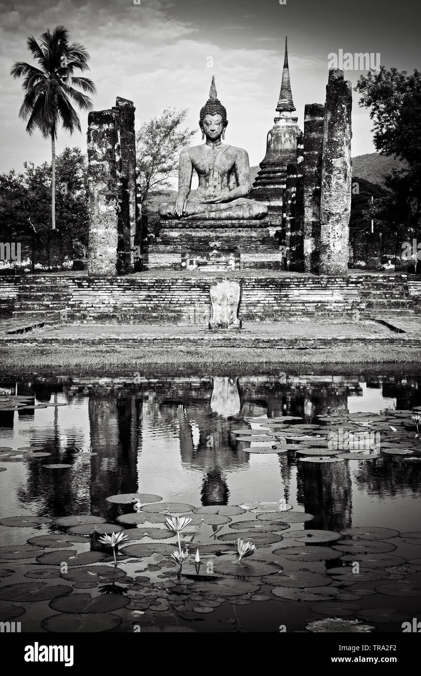 Black and white photo of Seated Buddha in meditation pose at Sukhothai Historical Park in Sukhothai northern Thailand. A UNESCO World Heritage Site Stock Photo