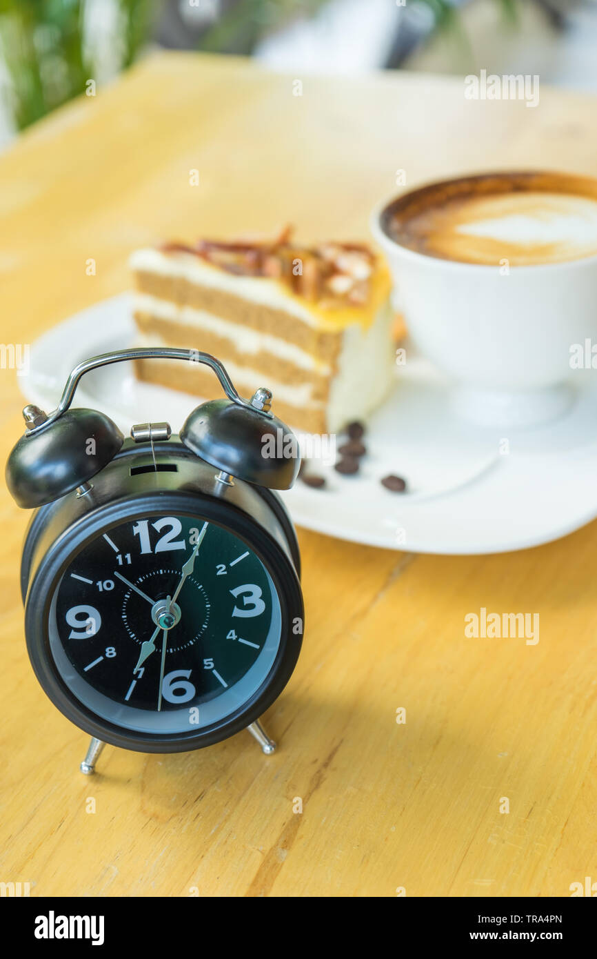 Alarm clock on table with blurred hot coffee background, Stock Photo