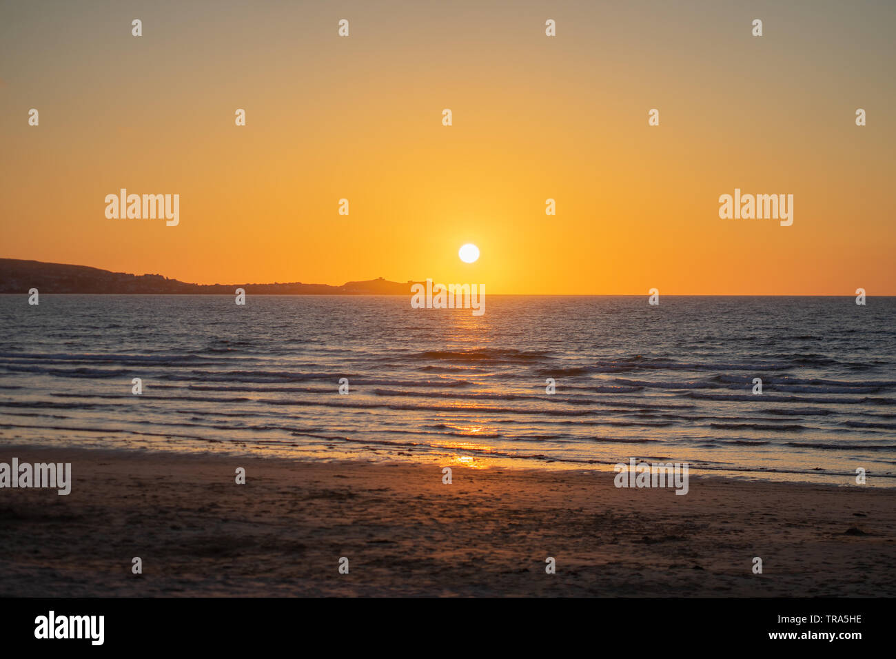 Sun setting across Cornish Beach on warm summers evening. Stock Photo