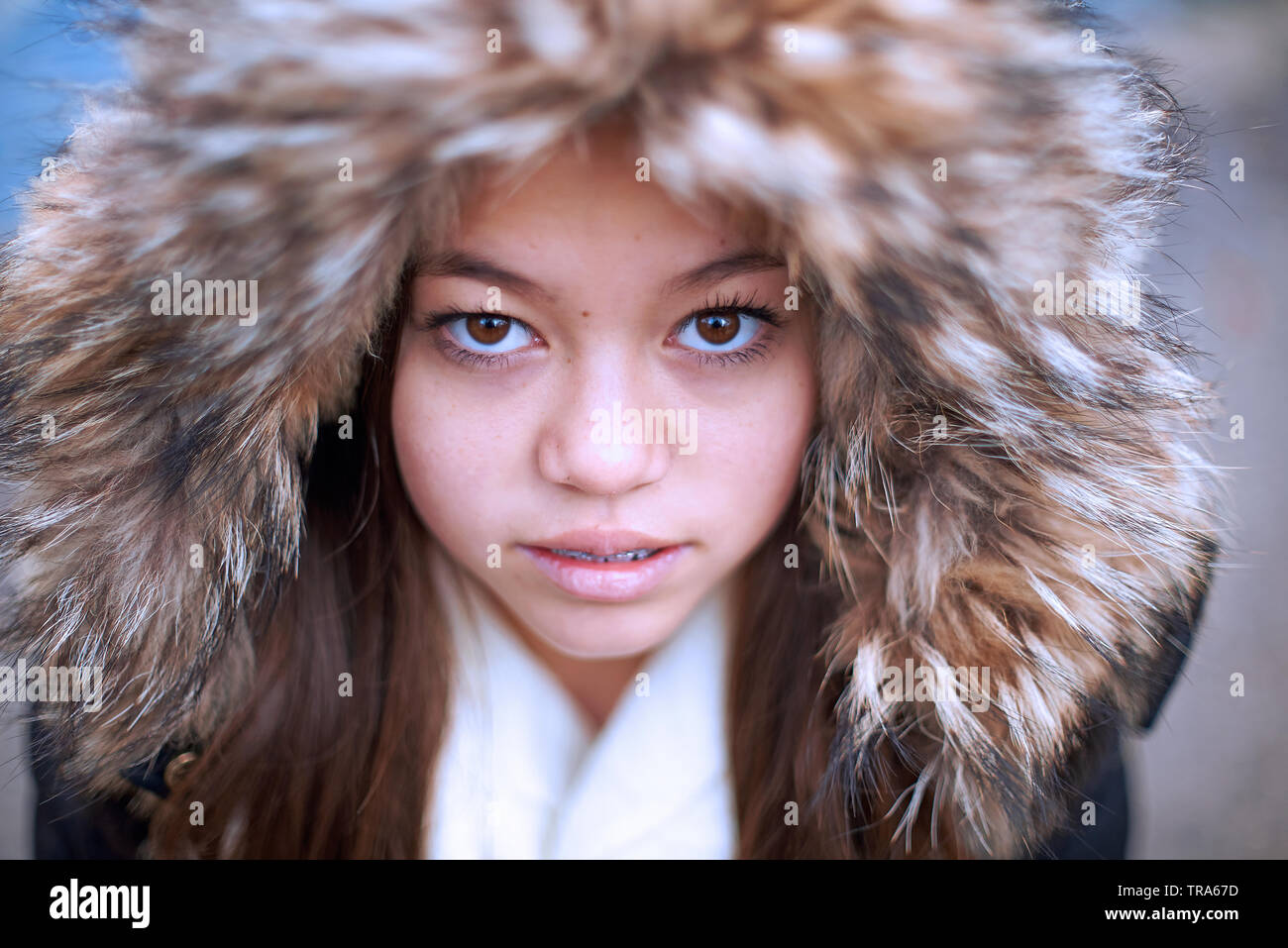 Portrait of a beautiful young Mixed Asian girl wearing a parka jacket coering her head in winter Stock Photo