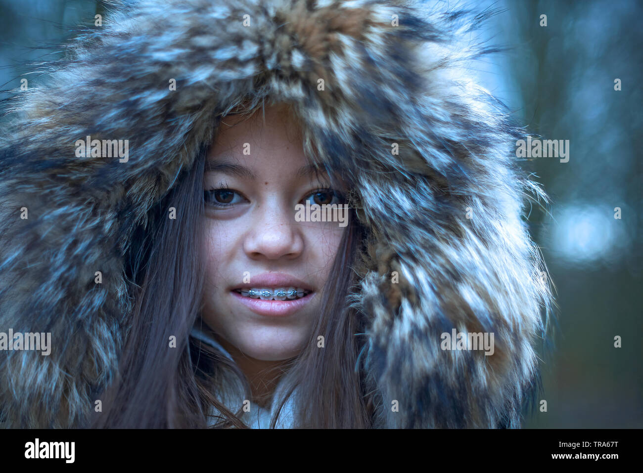 Portrait of a beautiful young Mixed Asian girl wearing a parka jacket coering her head in winter Stock Photo