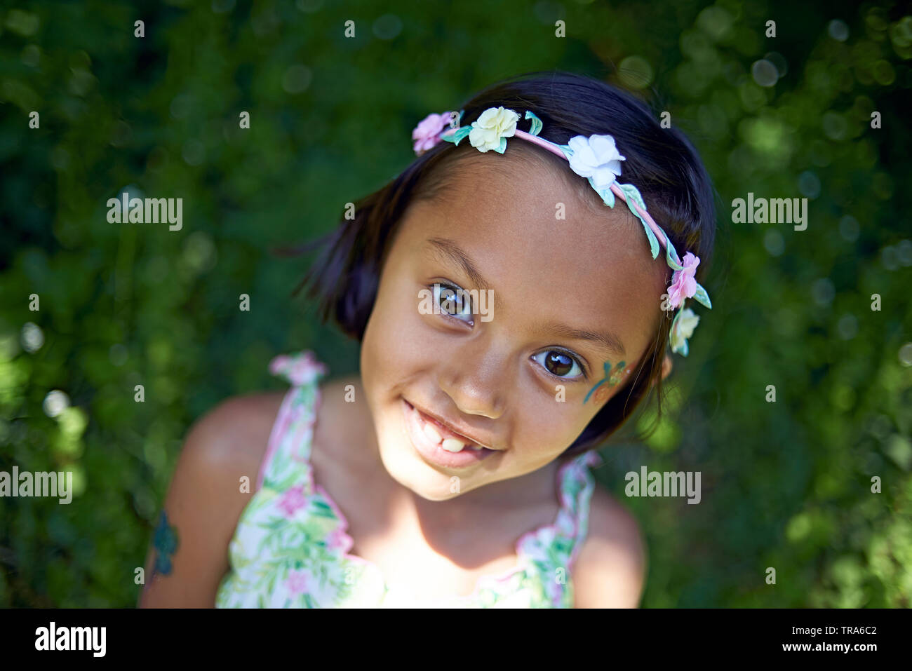 Amazing portrait of a young girl standing outside surrounded by nature looking in awe and excited whilst exploring and taking in all the beauty around Stock Photo