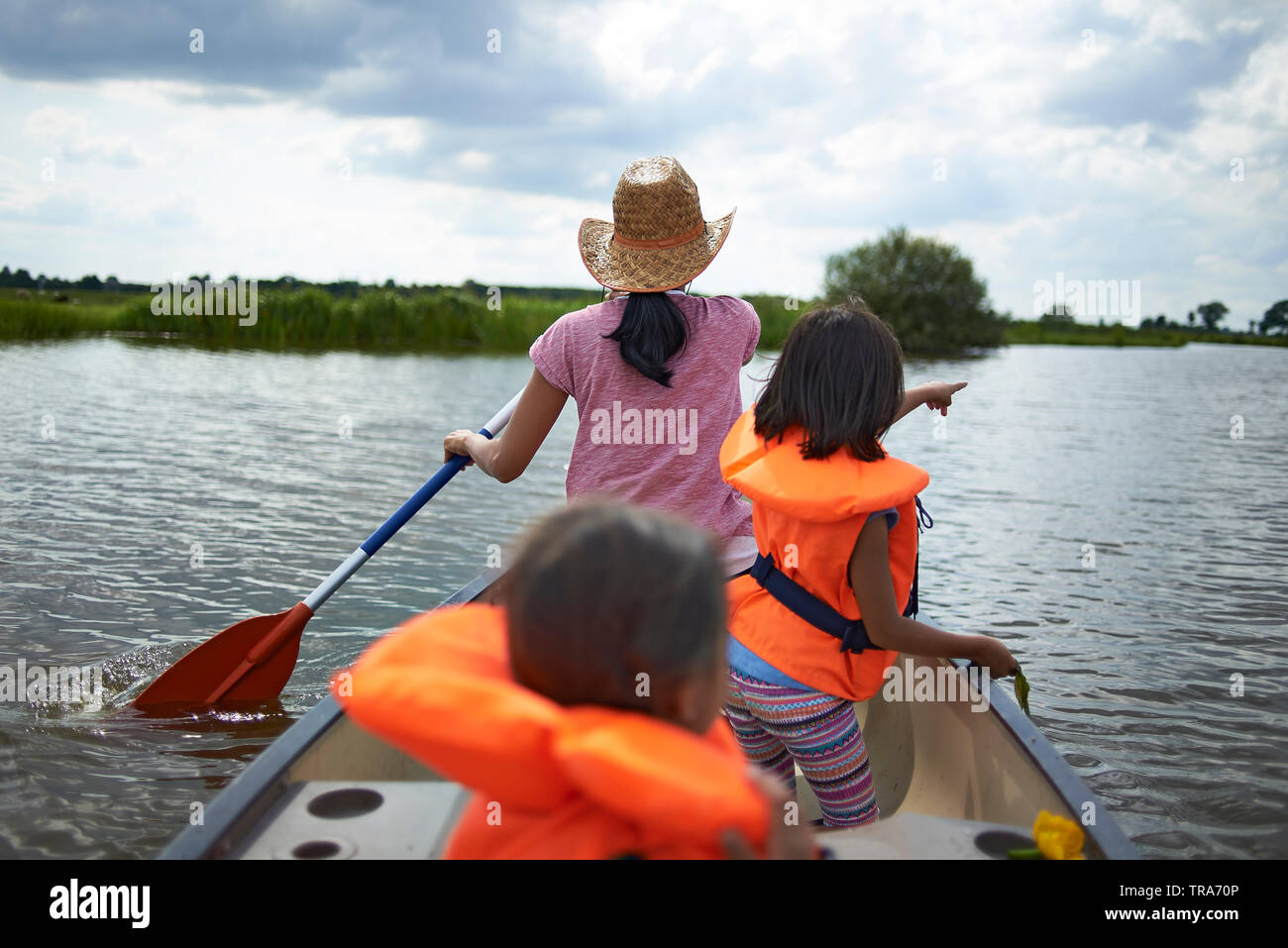 Asian mother paddling in a kayak with her two young children sitting