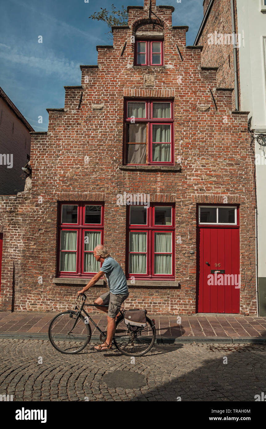 Brick old house and cyclist in Bruges. Charming town with canals and old buildings in Belgium. Stock Photo