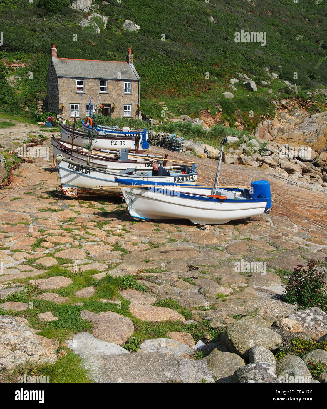 Typical Cornish cottage built on the quay at Penberth Cove on the Penwith Peninsula in west Cornwall, England, UK with fishing boats in the foreground. Stock Photo