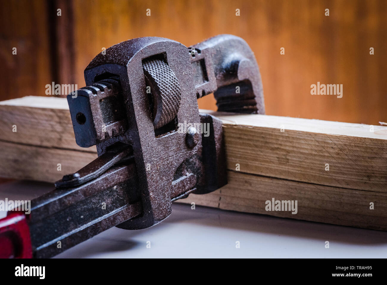 Rusted, stained pipe wrench hand tool clamped with a wooden block Stock Photo