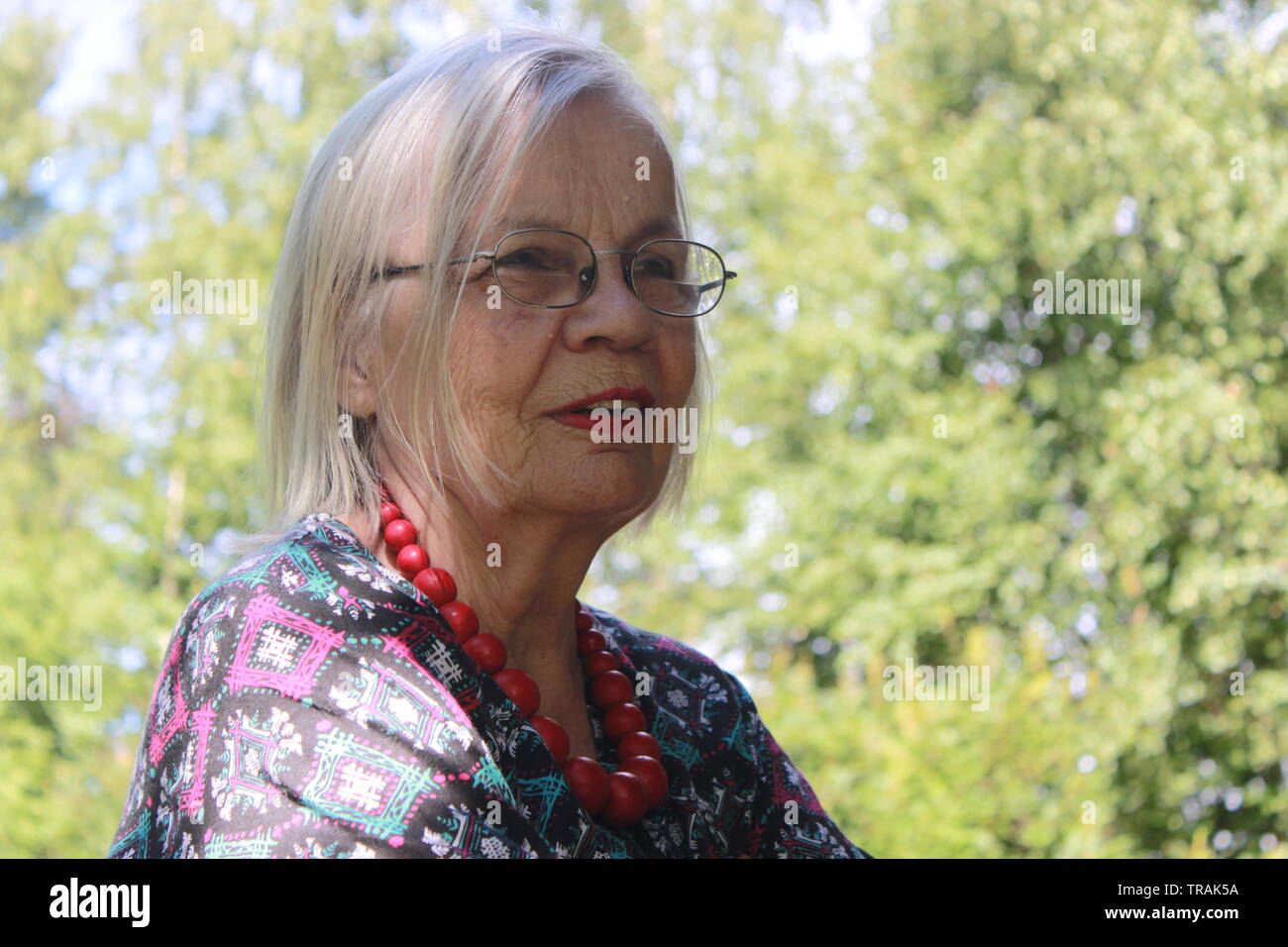 Portrait of a glamorous older lady in her 80s in a Finnish forest in the summer Stock Photo