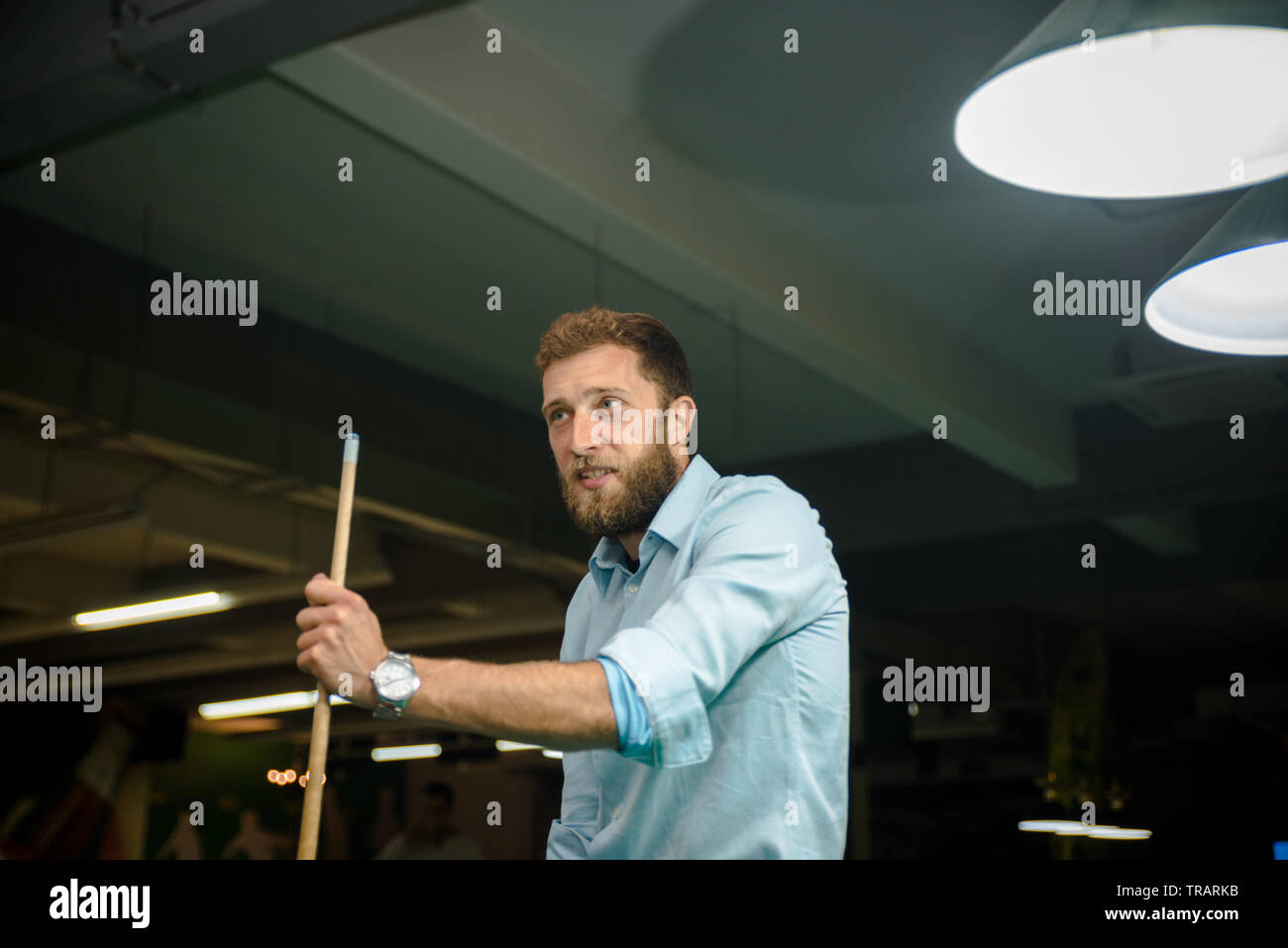 Young handsome man with beard plays billiards Stock Photo