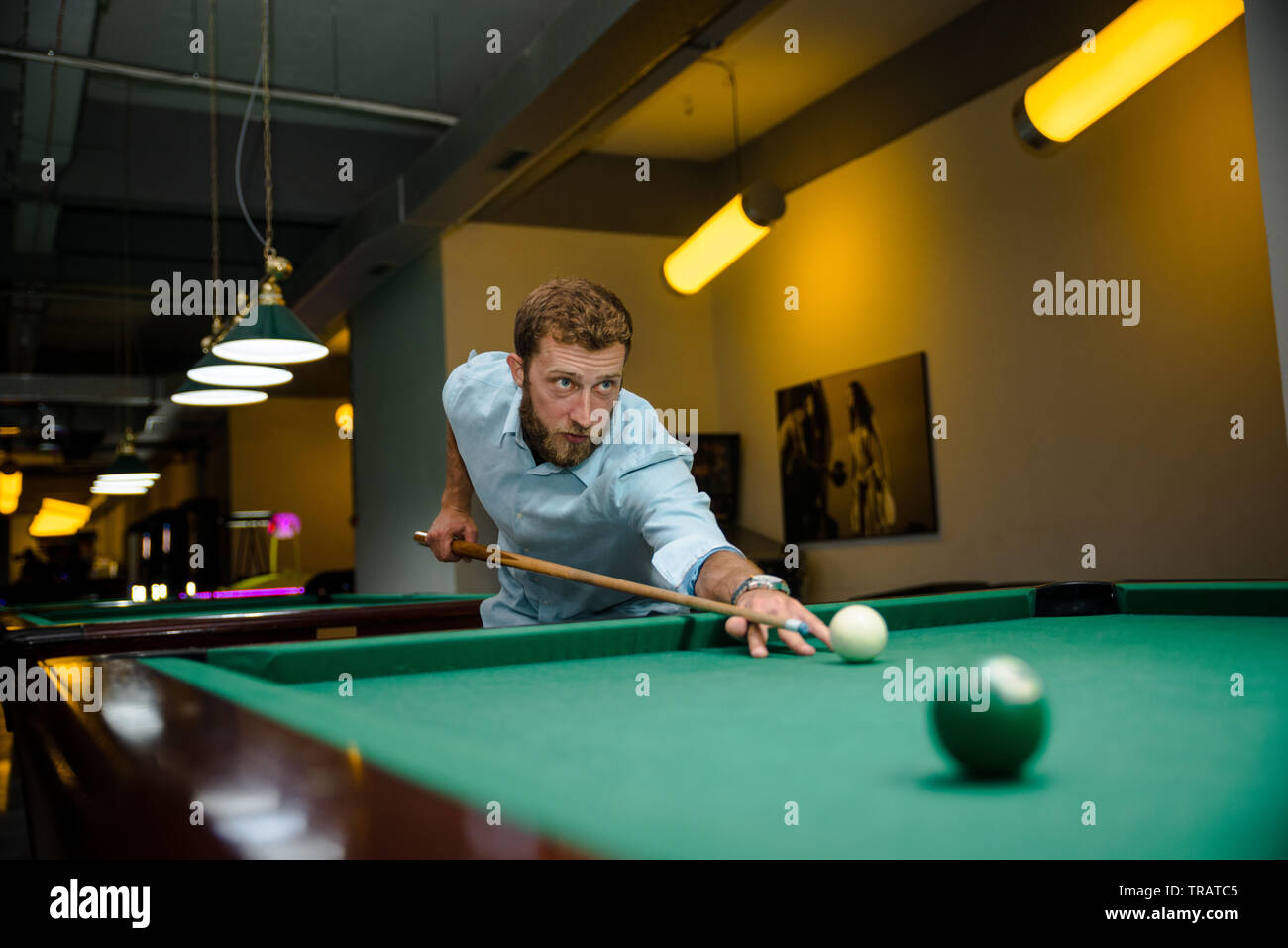 Young handsome man with beard plays billiards Stock Photo