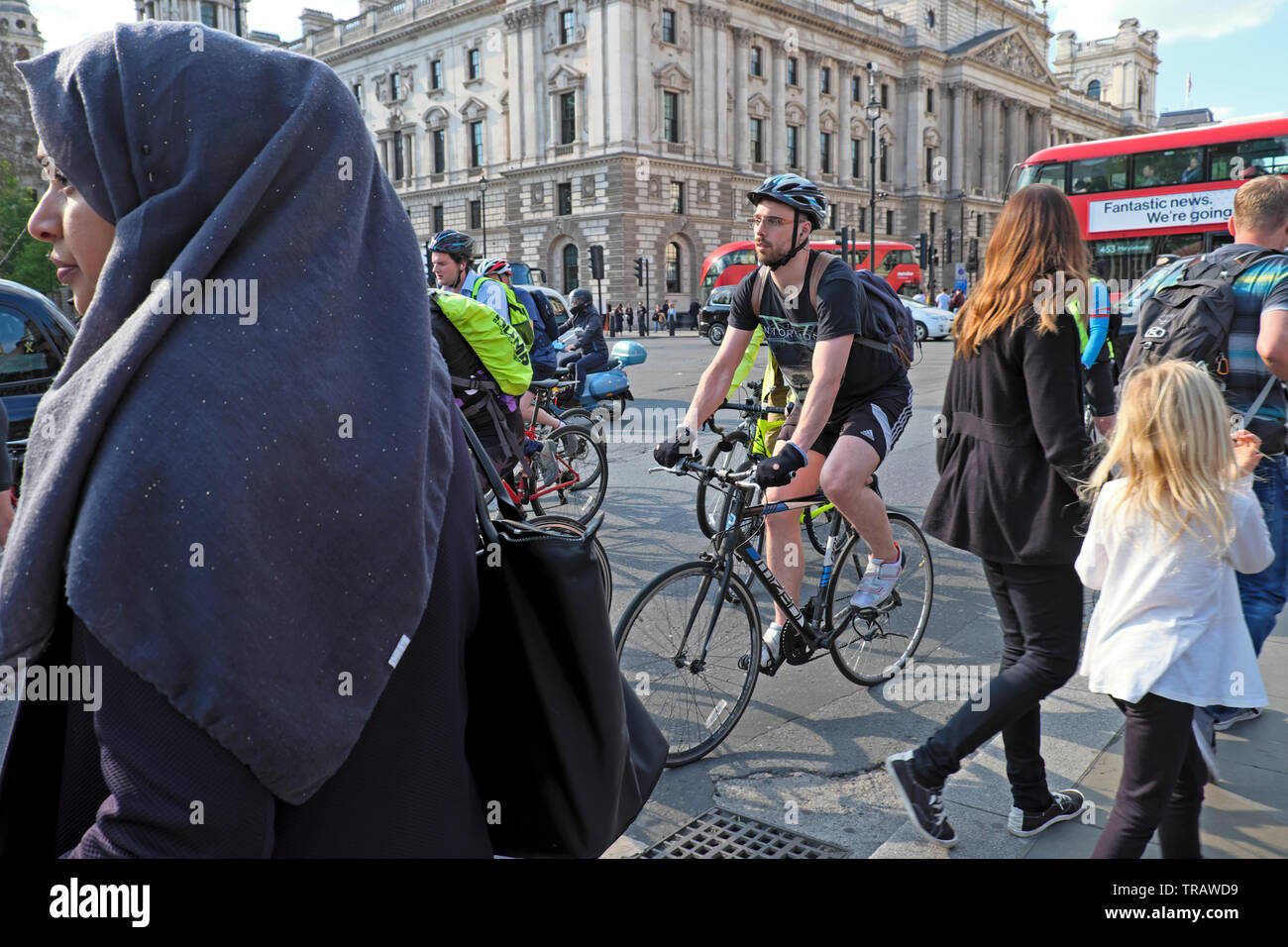 Woman in headscarf and cyclist cycling home in busy traffic after work riding bikes near Houses of Parliament Square Westminster London KATHY DEWITT Stock Photo