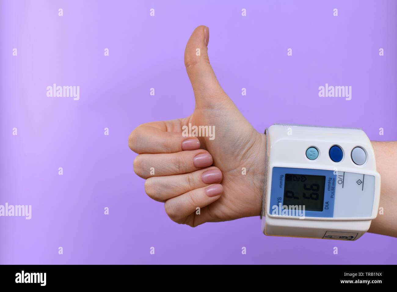 Arm and blood pressure monitor, buttoned at the wrist. In the center, from the bottom right corner. On a purple background. On the scoreboard heart ra Stock Photo