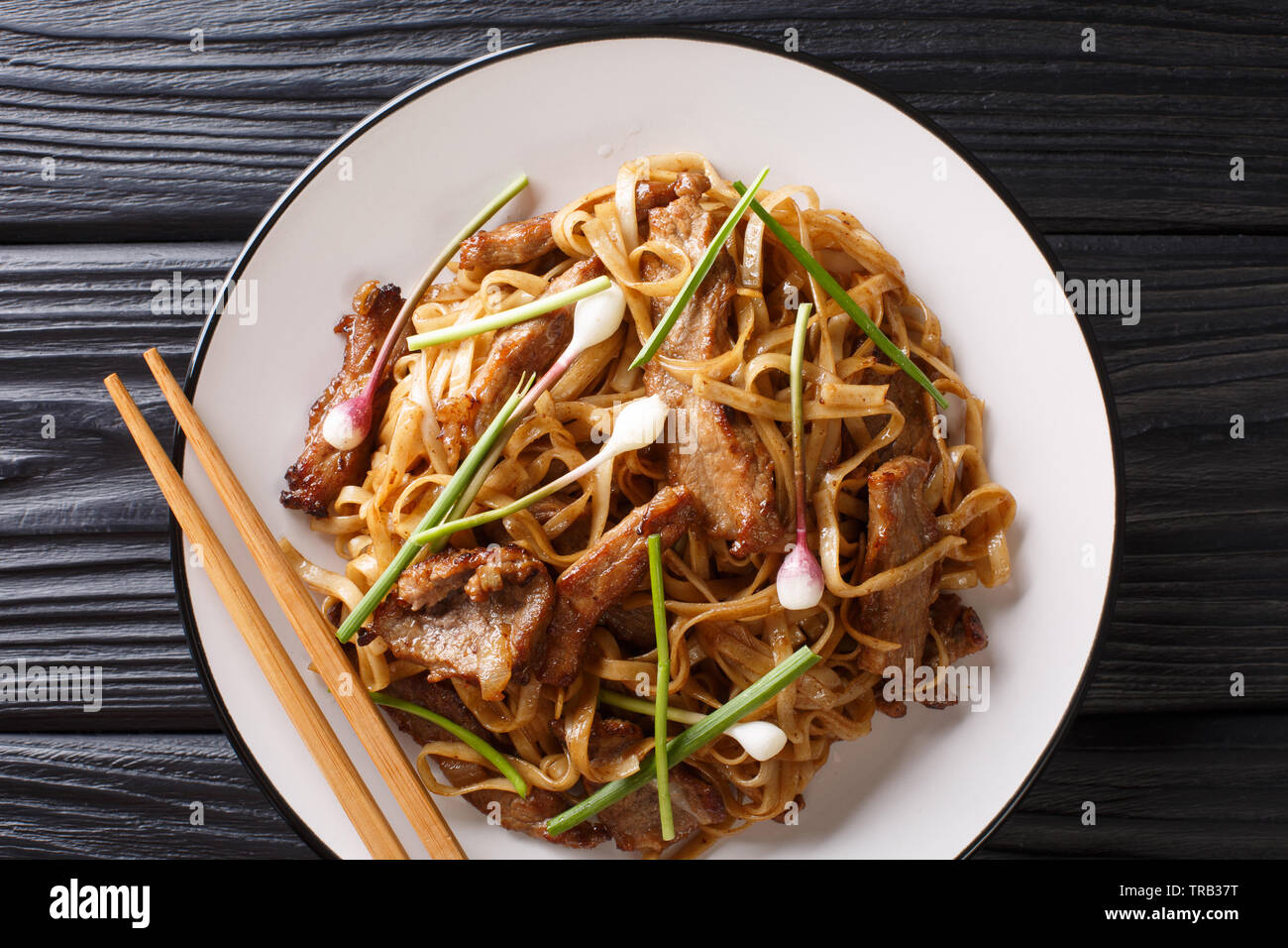 Beef Chow Fun Noodles (PanFried Ho Fun) Cantonese dish closeup on the plate on the wooden table