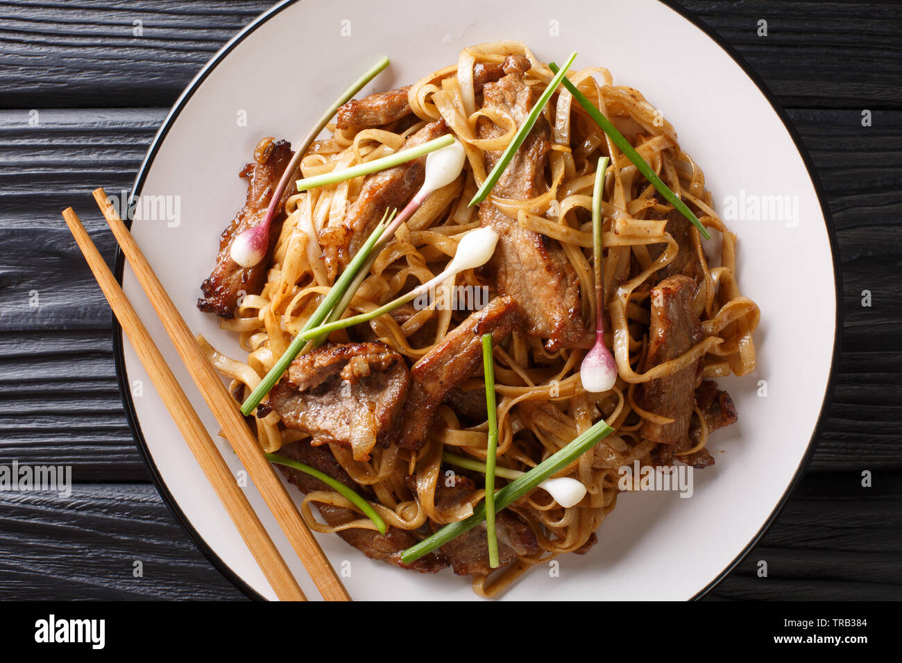 Beef Chow Fun - Beef stir-fried with rice noodle, bean sprouts, spring onions and Chinese chives is a famous Cantonese dish closeup on the plate on th Stock Photo