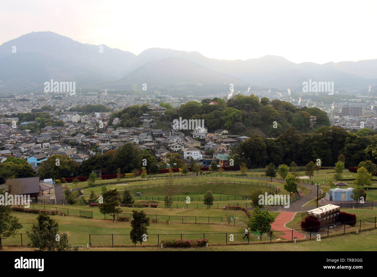 The landscape of Beppu in Oita and golf range as seen from a hill in sunset. Including the steam! Stock Photo