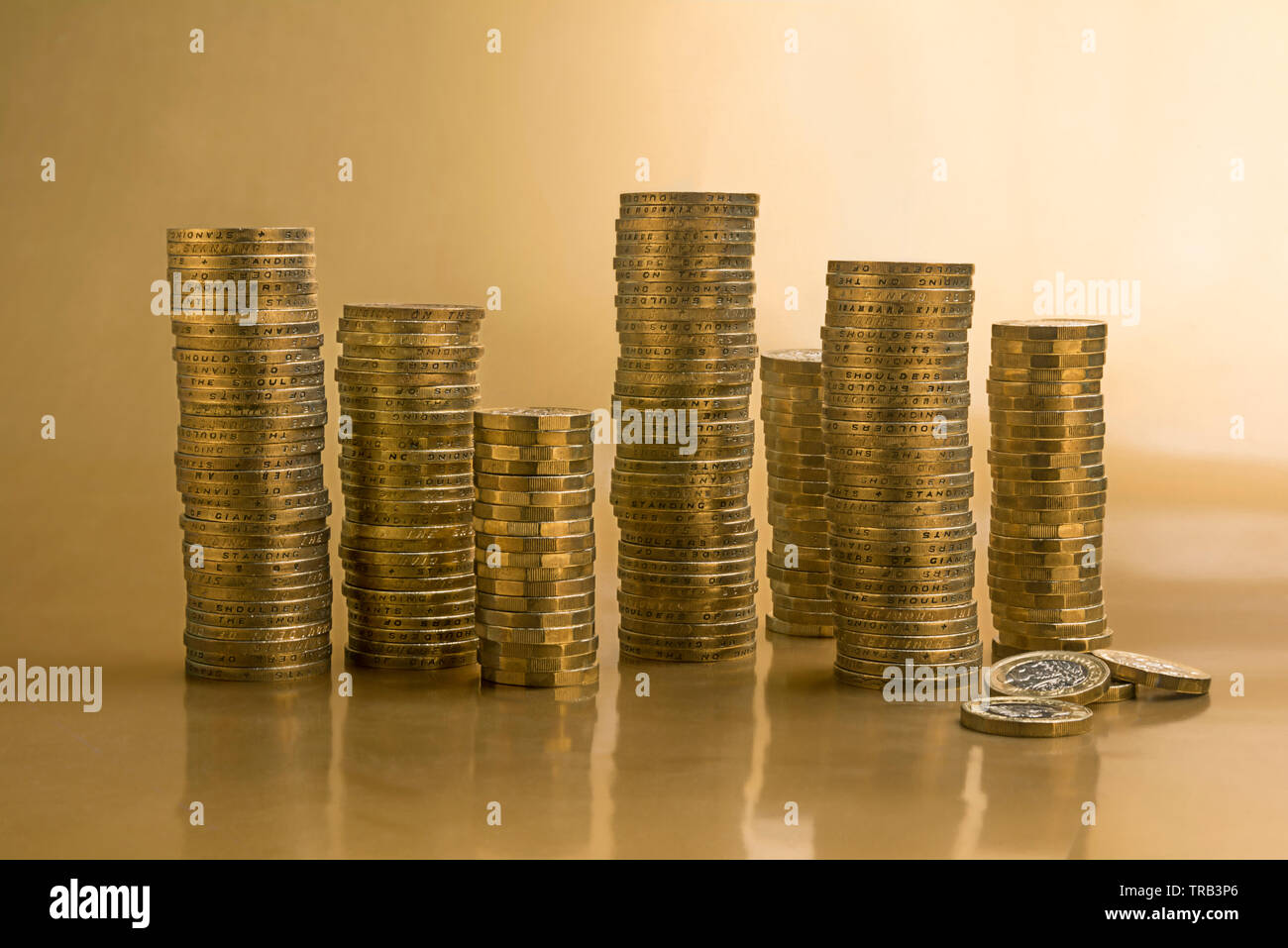 Stacked piles of one pound and two pound gold-colored coins Stock Photo