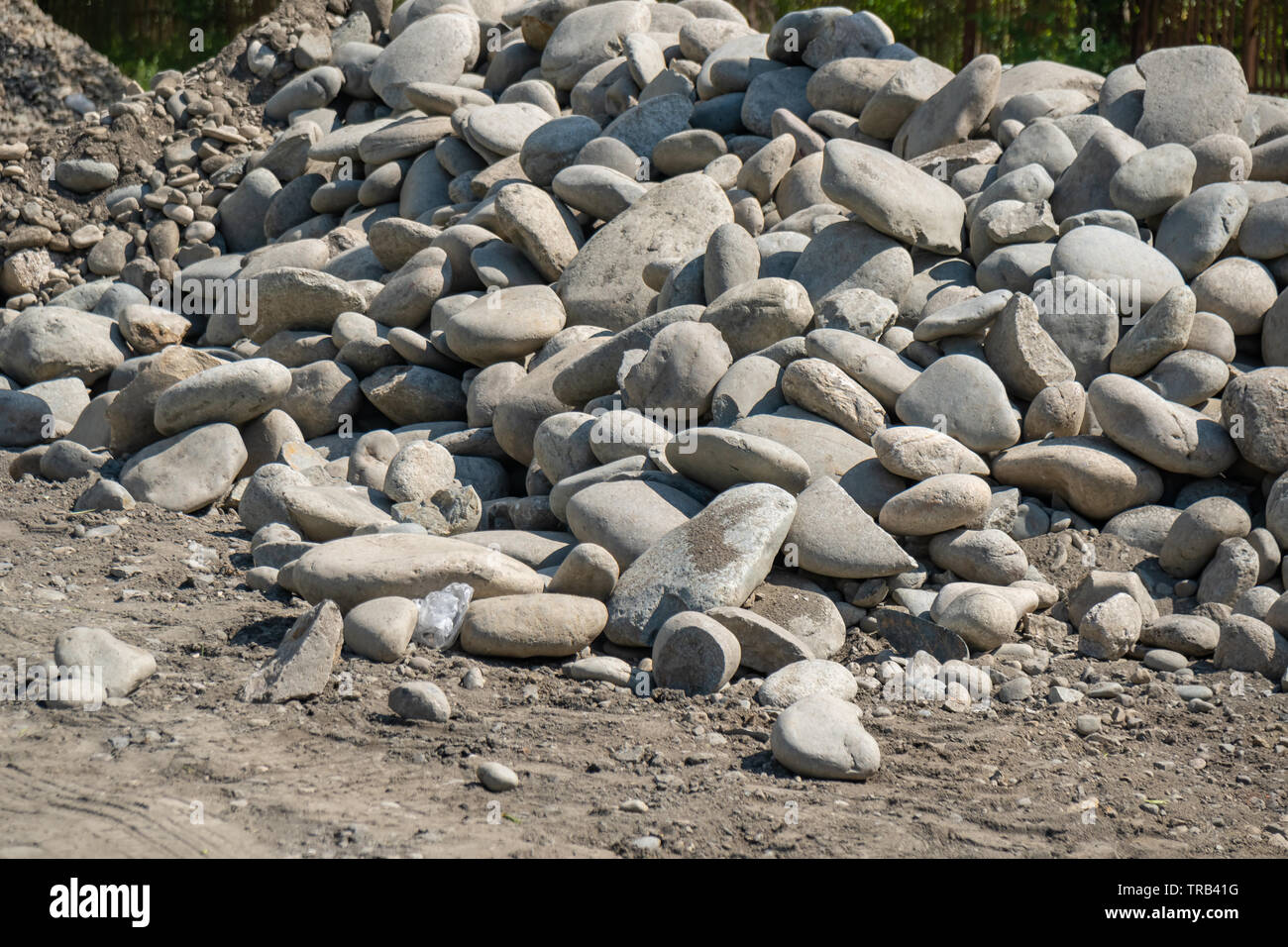pile of rounded stones piled in the side of the road. stones for road