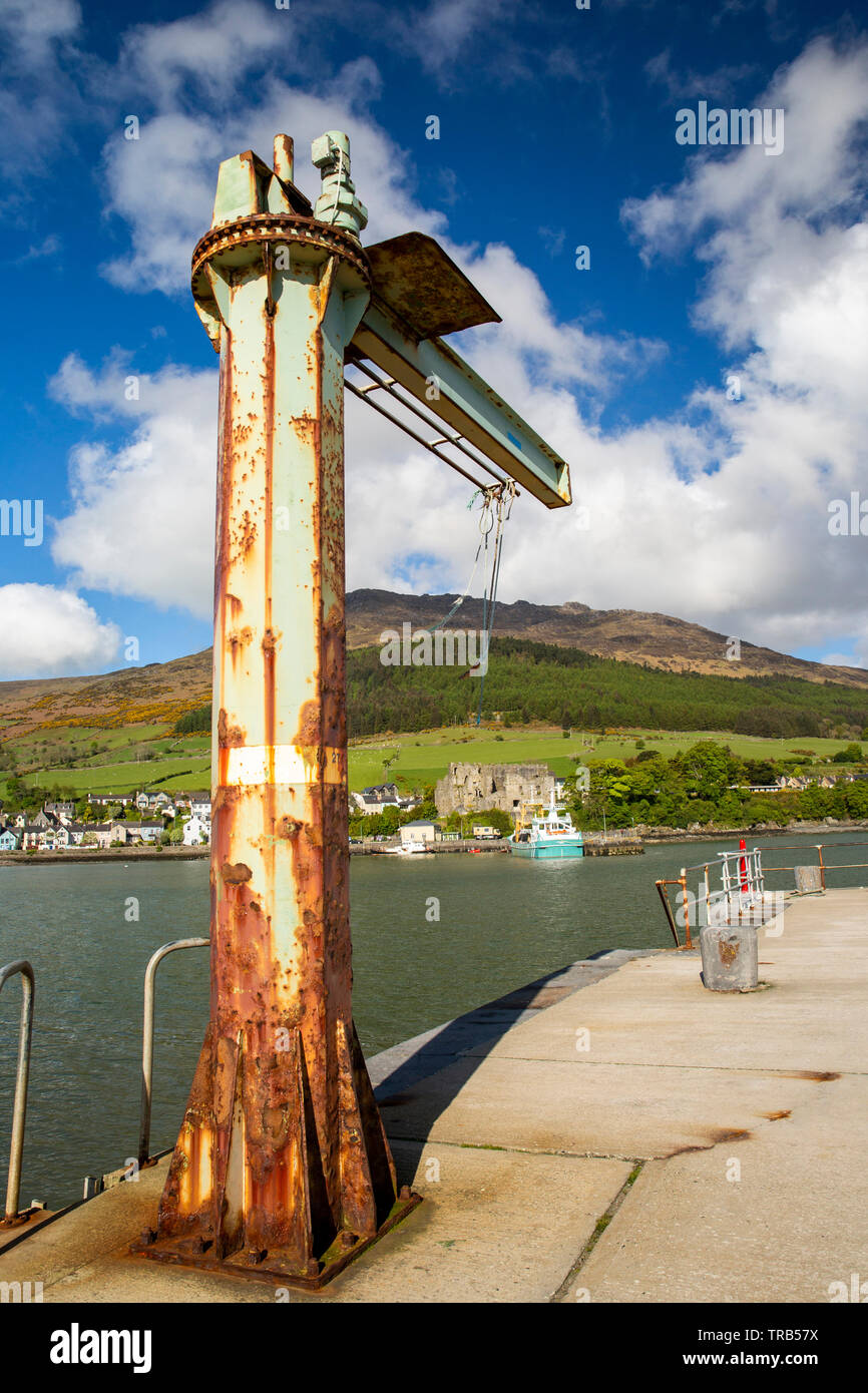 Ireland, Co Louth, Carlingford, harbour, old rusting quayside davit crane pointing towards St John’s Castle and Slieve Foye Stock Photo