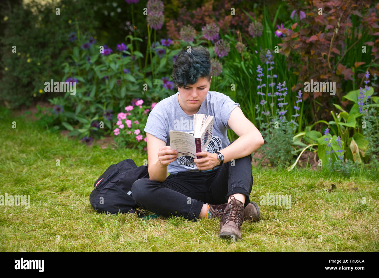 Visitor relaxing and reading a book on the lawn at Hay Festival Hay on Wye Powys Wales UK Stock Photo
