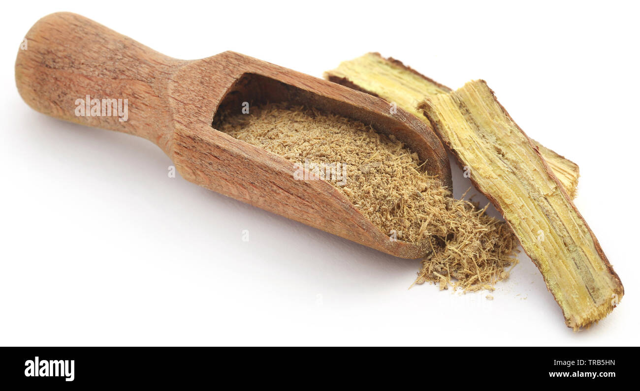 Liquorice stick and ground in a wooden scoop over white ackground Stock Photo
