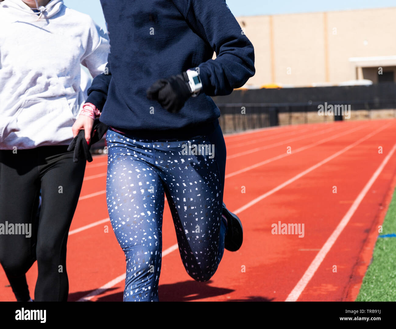 Two runners close up training on a track wearing blus and black spandex