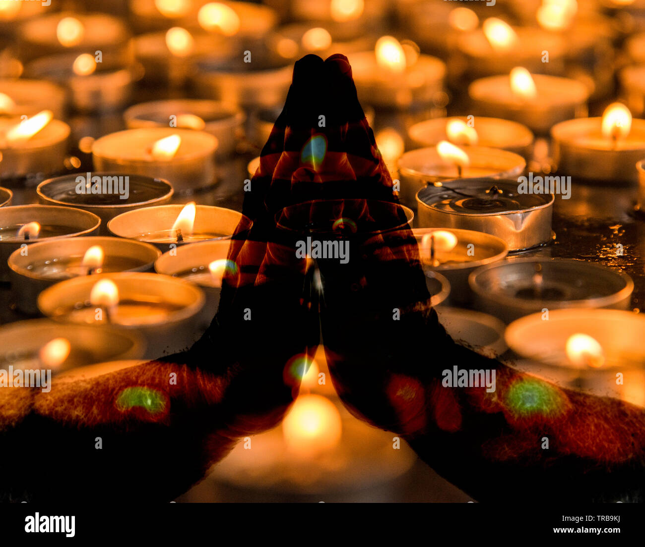 Praying hands over burning candles Stock Photo Alamy