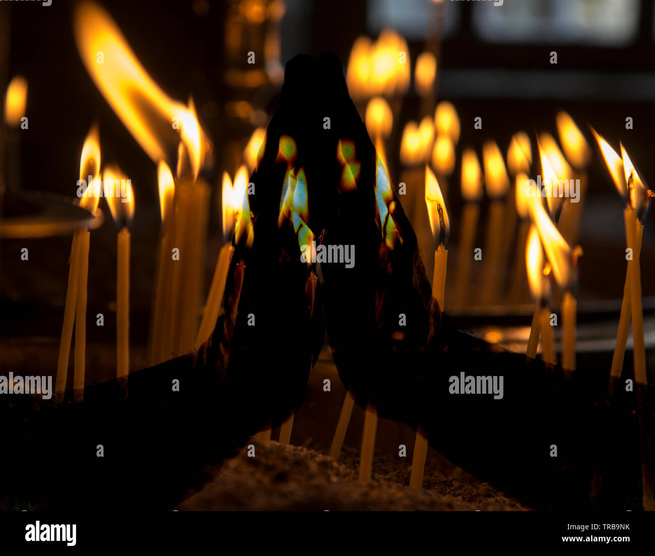 Praying hands over burning candles Stock Photo Alamy